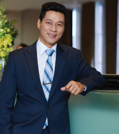 hotel owner with hand in pocket leaning on front desk